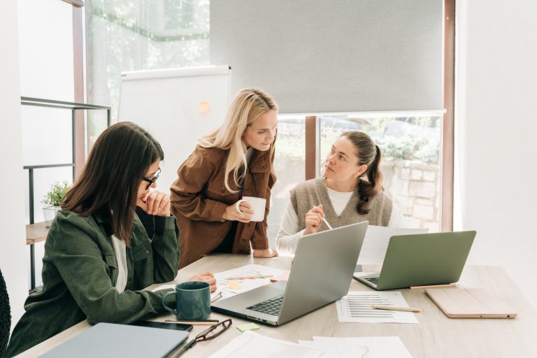Business colleagues discussing over computer at desk in office